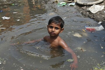 Poor Indian children bathe in the sewage water drain in the village