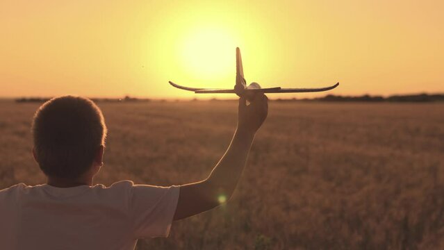 Boy plays with toy airplane, flying over field. Child dream, flight to future. Boy wants to become pilot astronaut. Slow motion. Child play with toy airplane. Teenager dreams of flying, becoming pilot