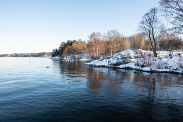 Swedish harsh beautiful winter concept: sunny view after snowfall. Lake coast during winter.