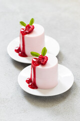 Valentine's Day dessert. Raspberry cream pudding. Panna Cotta. With raspberry sauce. On a plate. Light gray background. Close up