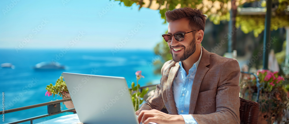 Poster a man sits at a table while using a laptop computer.