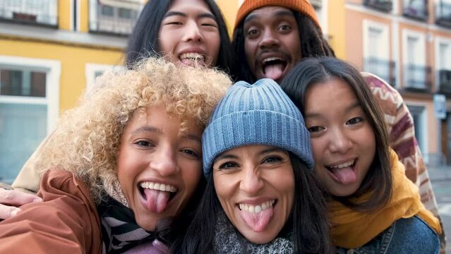 Multiracial friends group taking selfie pic with smartphone outside in autumn. Happy young people having fun walking on city street. Friendship concept with guys and girls enjoying outside.
