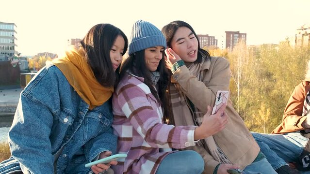 Group multiracial friends taking selfie picture with mobile smartphone outside. Happy young people smiling at camera. Youth concept with guys and girls having fun walking on city street.