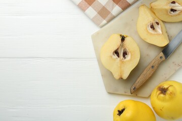 Tasty ripe quinces and knife on white wooden table, flat lay. Space for text