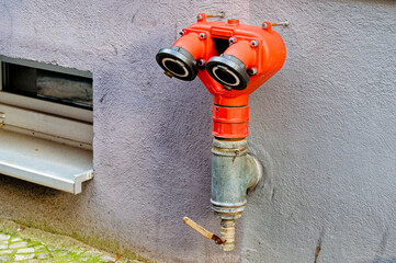 Fire hydrant with hose connection for the fire brigade on a building wall.