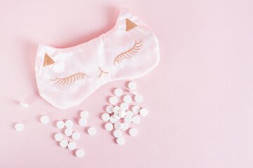 Obraz na płótnie Canvas Sleeping pills and sleep mask on pink background top view