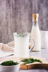 Obraz na płótnie Canvas Ayran homemade yogurt drink with dill in a glass on the table vertical view