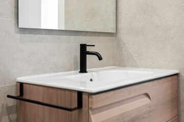 Close-up of a sink with a black tap and a mirror on the background of a gray stone wall. Concept new and stylish plumbing in new residential complexes ready for delivery