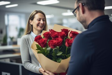 Businessman presents a bouquet of red roses to a female employee in a modern office