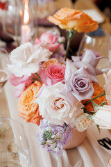 Beautiful spring and summer wedding table flower arrangement. Trendy pink, purple and orange roses. 