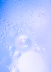 Abstract background in violet soft tones. Macro drops of oil on the surface of the water. Delicate cosmetic background for advertising products.