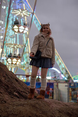 young cosplay woman on fun fare and Ferris wheel with magic winter lights