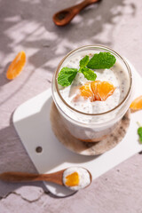 Glass and spoon with yogurt and glass of chia pudding made from vegan milk, seeds.
