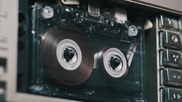 Audio tape recorder playback vintage transparent audio cassette close-up. Retro recorder. Record player playing an old tape. Retro tape reels rotate in a deck. Rec conversations, calls, archive, 80s