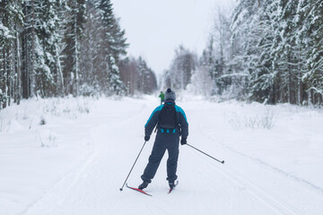 Fototapeta na wymiar People ski in winter on a ski track through a winter forest.Cross Country skiing.