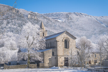 Beautiful abbaye of Leoncel under the snow surrounded by frozen trees and white mountains on the background. France 2024