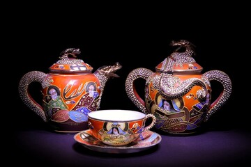 A sugar bowl jug and a cup made of Chinese porcelain standing on a dark background.