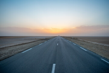 Beautiful colourful sunset over endless empty road in middle of desert. Asphalt highway in Tunisia,...