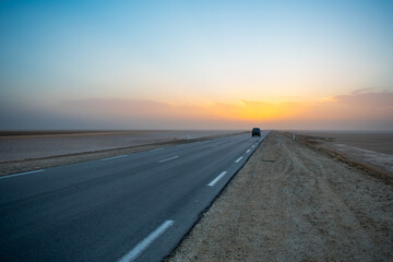 Beautiful colourful sunset over endless empty road in middle of desert. Asphalt highway in Tunisia, North Africa.