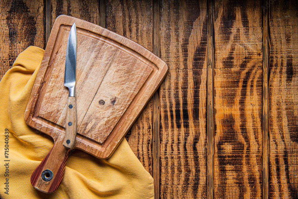 Wall mural empty wooden cutting board, knife and napkin on wooden background. Preparation of home cooking. Space for text.