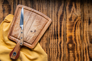 empty wooden cutting board, knife and napkin on wooden background. Preparation of home cooking. Space for text.