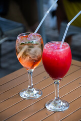 close up of drink glasses in a square with trees in the center red and rosatto on a bistro table
