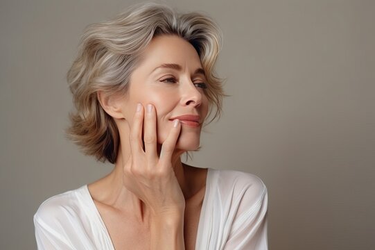 portrait of a beautiful woman 50 years old with natural makeup in a beige T-shirt on a neutral background. The concept of natural beauty and anti-age care