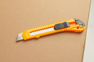Box cutter on a parcel cardboard box. Retractable utility knife