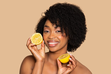 Smiling woman with fresh lemon halves for natural skincare