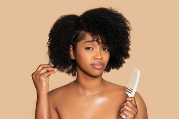 Sad black woman touching her curly hair and holding comb