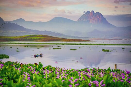 The sun rises over a beautiful lake, with mountains and colorful flowers in the background. Clouds are moving, birds and butterflies are flying around. Perfect for wallpaper or natural background 