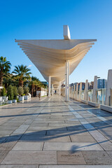 A modern port promenade lined with palm trees, with fountains, sculptures and restaurants. Malaga, Spain.