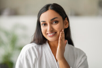 Closeup of cheerful millennial indian woman touching her face