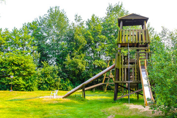 Wooden tower with slide and stairs on playground in park.