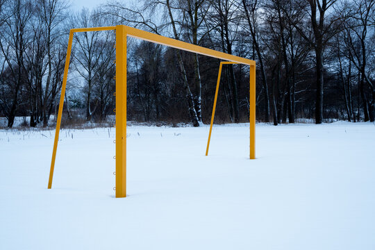 Yellow football goals on white snow against a background of trees.