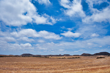 Fototapeta na wymiar Characteristic landscape in the northern part of the Western Australian Wheatbelt, between Geraldton and Northampton. Rolling fields an barren hills under a blue sky with white clouds