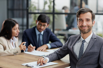 young man posing for the camera while sitting at the table in the office