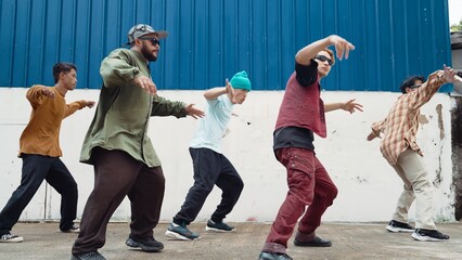Group of hip hop choreographer dancing street dance together at wall. Young break dancer practicing...
