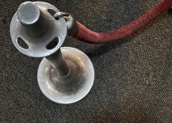 A vintage metal stanchion with a maroon velvet rope 