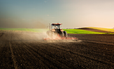 Fototapeta premium Farmer in tractor preparing land for sowing