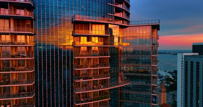 Mirror windows of the skyscrapers facades reflect orange light at sunset. Miami uptown buildings at dusk.