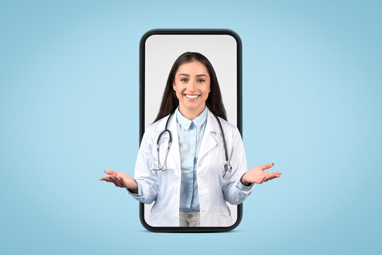 Friendly european female doctor with stethoscope emerges from smartphone screen, engaging with welcoming gesture