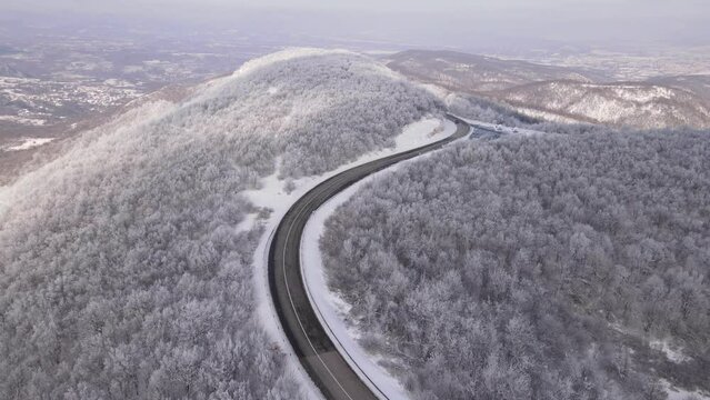 Car drive in snow winter day on the road in mountain range aerial view