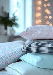 a stack of pillows. pillowcases in pastel blue, pink, mint colors with small checks and stripes on a white background of a blurred bedroom.