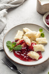 Lazy dumplings, vareniki with raspberry jam, almond petals and mint leaves close up. Boiled cottage...