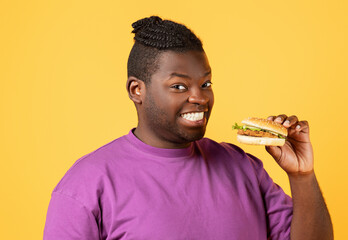 Black Man Holding Big Tasty Burger In Hand, Yellow Backdrop