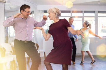 Couple of adult man and elderly woman dancing twist in studio