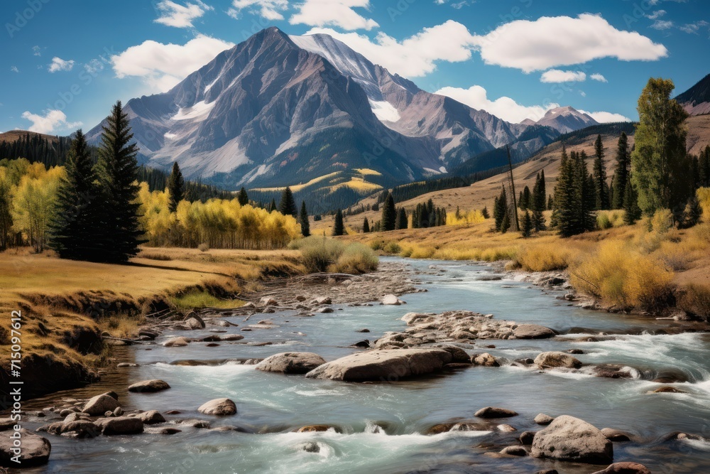 Poster a painting of a mountain with a river running between it and a grassy area with rocks in the foregro