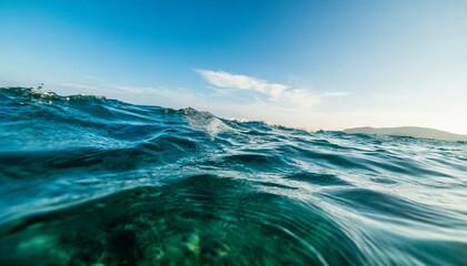 Ocean waves with sun, sky, and clouds in the background