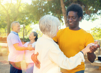 Obraz premium Smiling elderly woman enjoying dance with partner in garden